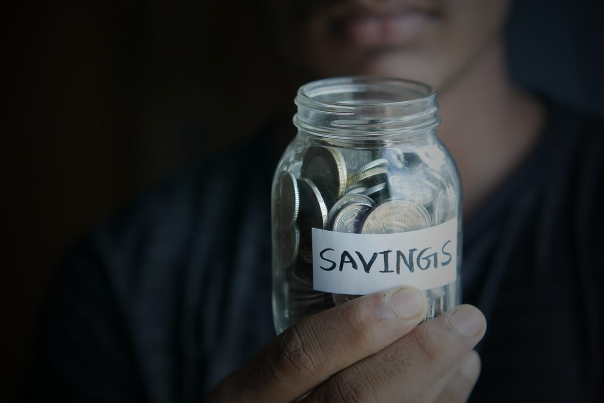 A person holding up a savings jar with coins inside